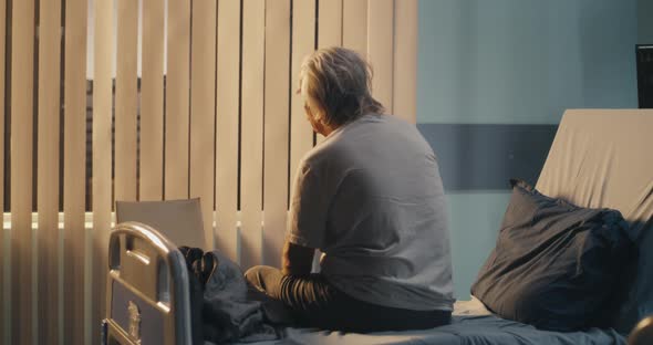 Depressed Aged Patient Sitting on Bed alt