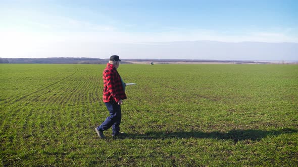 Senior Agronomist Man Looks at a Fresh Green Field After Winter. Smart Farming, Using Modern alt