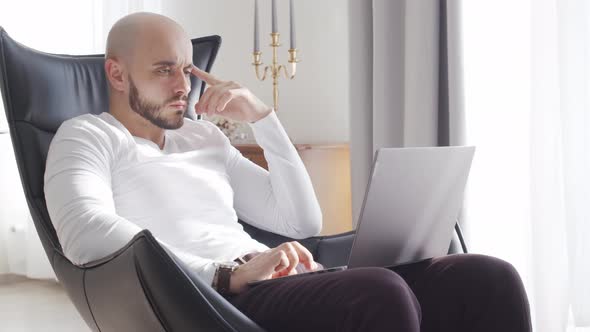 Bearded businessman working at home sitting in armchair. Business and investments concepts. alt