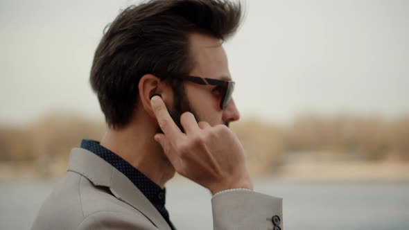 Man Relaxing And Using Wireless Headphones And Listening Music From Smartphone On Nature. alt