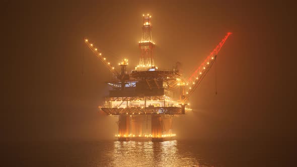 Oil rig on an open ocean during a foggy night. Countless lights illumination. 4K