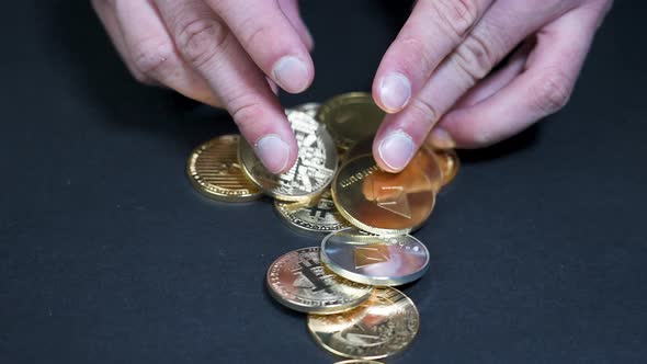 Male hands playing with various gold cryptocurrency coins,dark surface. alt