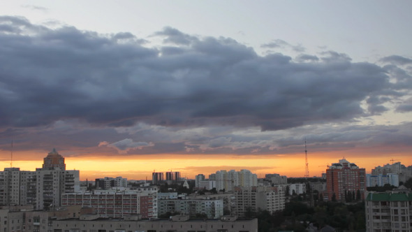 Time-lapse of passing clouds at sunset over city