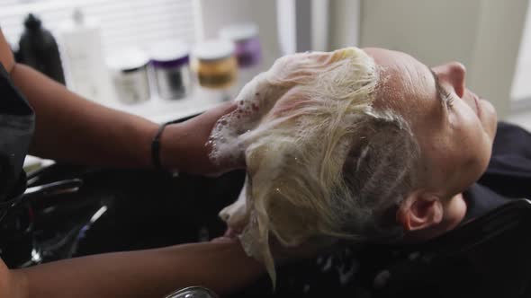 Rear view woman having her hair washed by a hairdresser alt