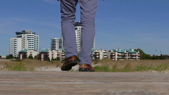 A Man Walks by a Wooden Walkway to Town alt