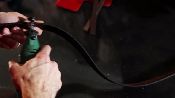 Leather Workshop  a Man Grinds the Edges of a Leather Belt Using a Tool alt