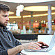 Man Working at a Laptop in a Shopping Center Man Working at a Laptop in a Shopping Center - VideoHive Item for Sale