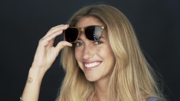 Woman putting on sunglasses and tossing hair alt