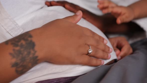 Closeup Pregnant Belly of African American Young Woman with Hands Caressing Tummy alt