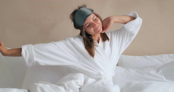 Pretty Woman Stretches and Puts on Sleep Mask Sitting on Bed