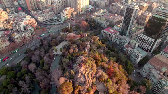 Aerial orbit of Santa Lucia Hill with autumnal trees, traffic in Alameda avenue, Santiago city build alt