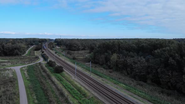 Dutch train passing on a railway track on a summer day in the netherlands, Drone shot alt