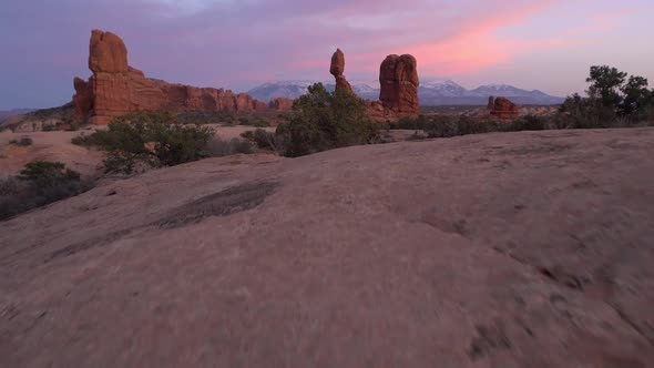 Rising view from behind rocks to view Balanced Rock in the Utah desert alt