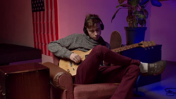 Young Male Musician in Headphones Playing Guitar