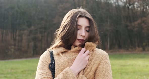 Portrait of Young Attractive Female Who Smiling and Looking at the Camera on Green Lawn. Cheerfully
