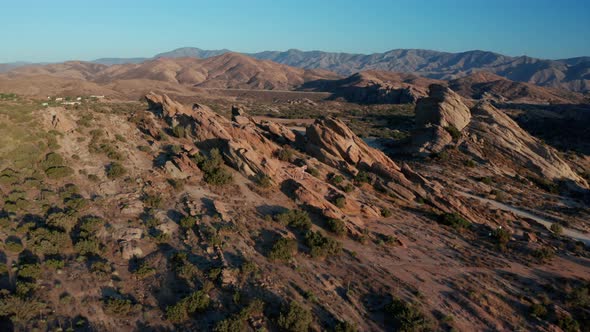Aerial footage of mountains and dry land with blue cloudy sky in the background.  alt