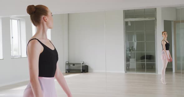 Caucasian female ballet dancer practicing ballet during a dance class in a bright studio alt