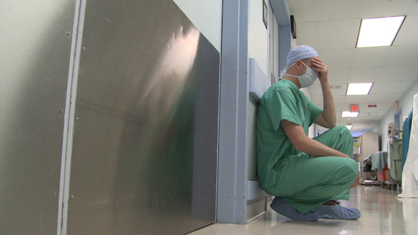 A Young Surgeon Kneels Outside The Operating Room