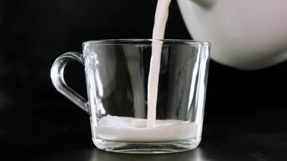 Cold milk is poured into a glasson black background. Close up