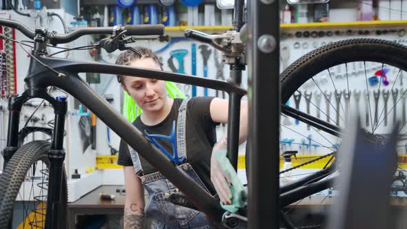 Female Technician Cleaning Bicycle in Repair Shop