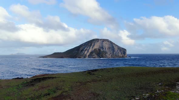 drone flying back away from mini island above another hawaiian island alt
