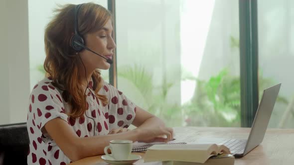 Side View of Young Business Woman Wearing Headset Communicating By Video Call alt