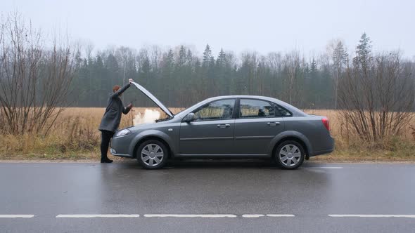 A Young Woman a Broken Car and Opens the Hood in the Forest alt
