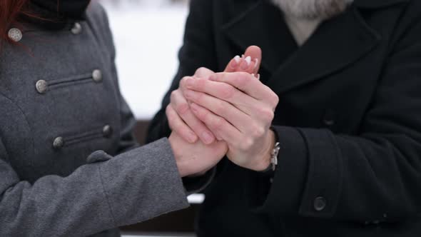 A respectable adult man warms the hands of his lady - a young beautiful woman alt