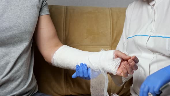 Nurse Cuts Gypsum Bandage From Healed Arm of Young Man alt