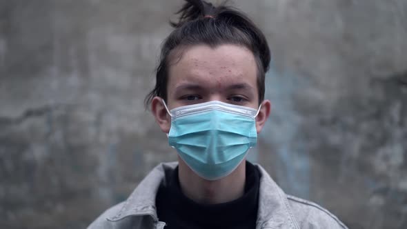 Teen Boy Putting Medical Protective Face Mask Looking at Camera