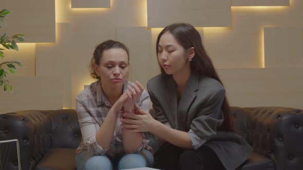 Asian Woman Psychologist Consoling Depressed Female Patient During Psychotherapy alt