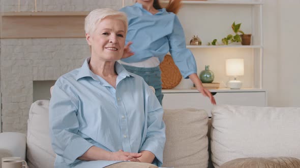 Elderly Hoary Grandmother Sits on Couch Smiling Little Gymnast Granddaughter Having Fun Doing alt