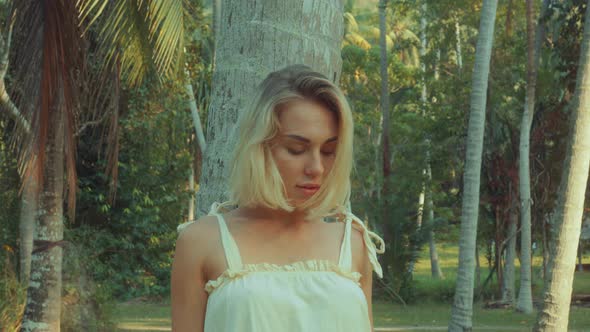 Young Blonde Standing Contemplating Tropical Rainforest Sunset Light Coming From Above alt