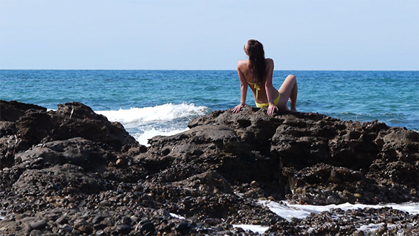 Young Attractive Woman Sitting On The Rocks
