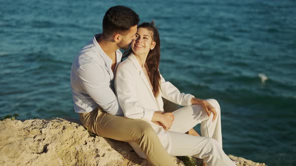 Smiling Ethnic Couple Talking on Rock Against Sea alt