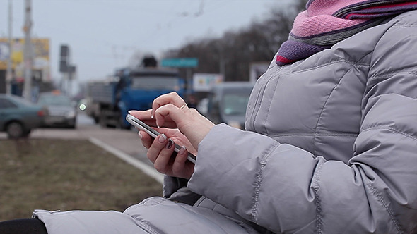 Woman Using Her Smartphone Sitting In Outdoor alt