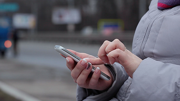 Young Woman Chatting with Smartphone on Street alt
