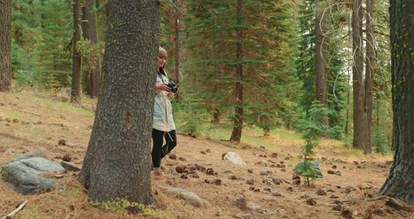 Woman Photographer Walks By Green Forest on Sunny Fall Day and Taking Pictures alt