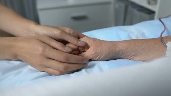 Caring Daughter Holding Hand of Terminally Ill Mother With Chemotherapy Dropper