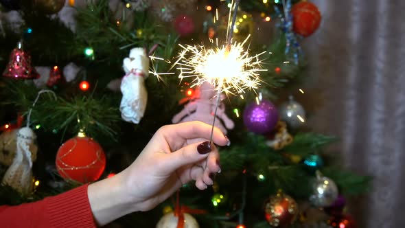 A Girl Holds a Sparkler Against the Background of the Christmas Tree Slow alt