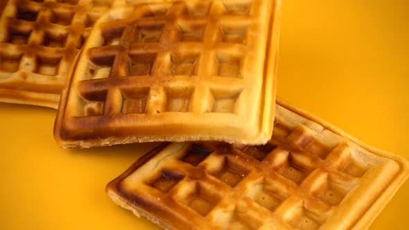 Belgian waffles are falling down on a yellow background. Slow motion. alt