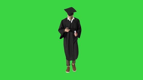 Smiling Student Walking and Texting on His Phone on a Green Screen, Chroma Key. alt