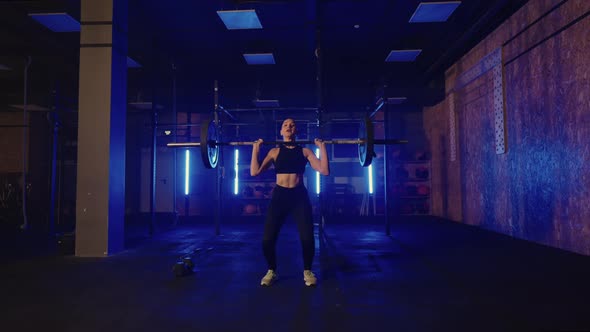 Female Powerlifter is Training in Gym Alone in Night Lifting Heavy Barbell Tensing Muscles of Arms alt