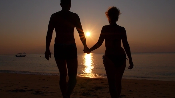 Romantic Couple Holding Hands At Sunset On Beach