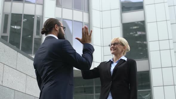 Male and Lady Colleagues Giving High-Five After Successful Business Meeting, Win