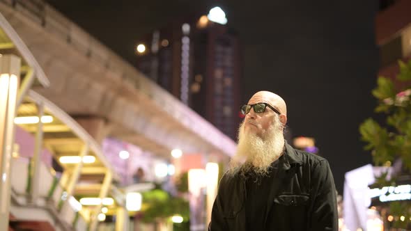 Mature Bearded Tourist Man Checking Time Against View of the City at Night