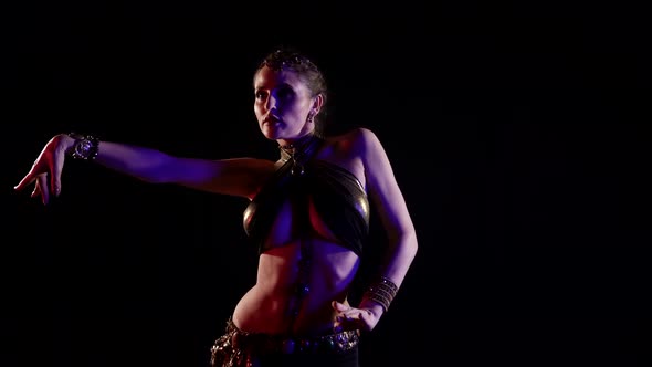 A Woman Who Dances an Oriental Dance on a Black Background Makes Beautiful Movements with Her Hands alt