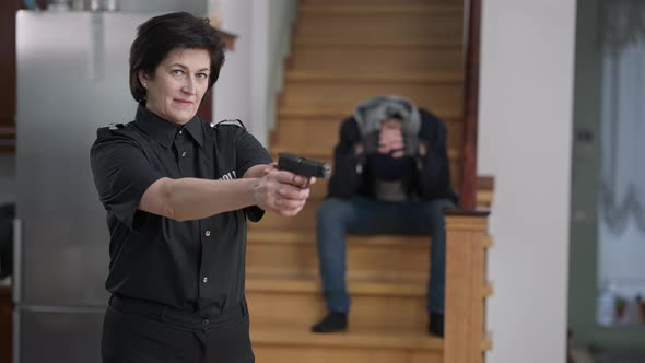 Portrait of Confident Female Police Officer Raising Hands with Gun Looking at Camera As Unfortunate alt