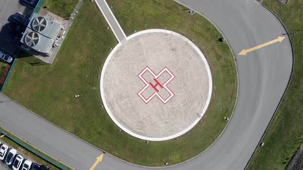 Aerial Overhead View of a Helipad at a Hospital, Drone Rising Spin Shot on a Sunny Day alt