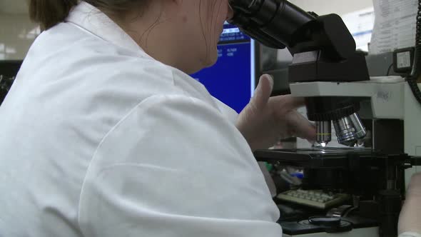 Female Lab Technician Looks Through Microscope (2 Of 3)